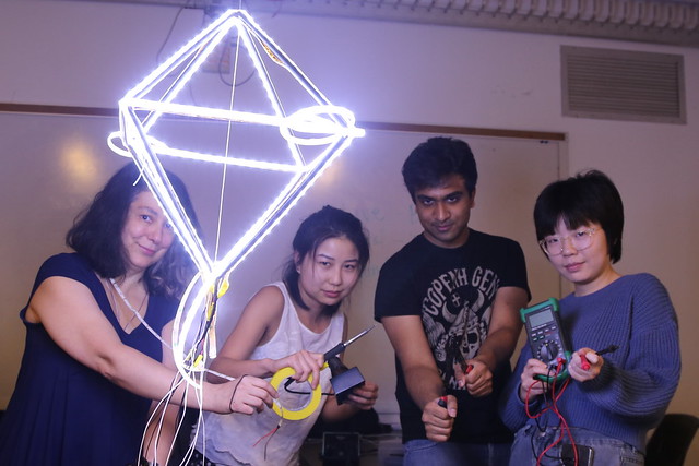 a group of campers creating a light sculpture together