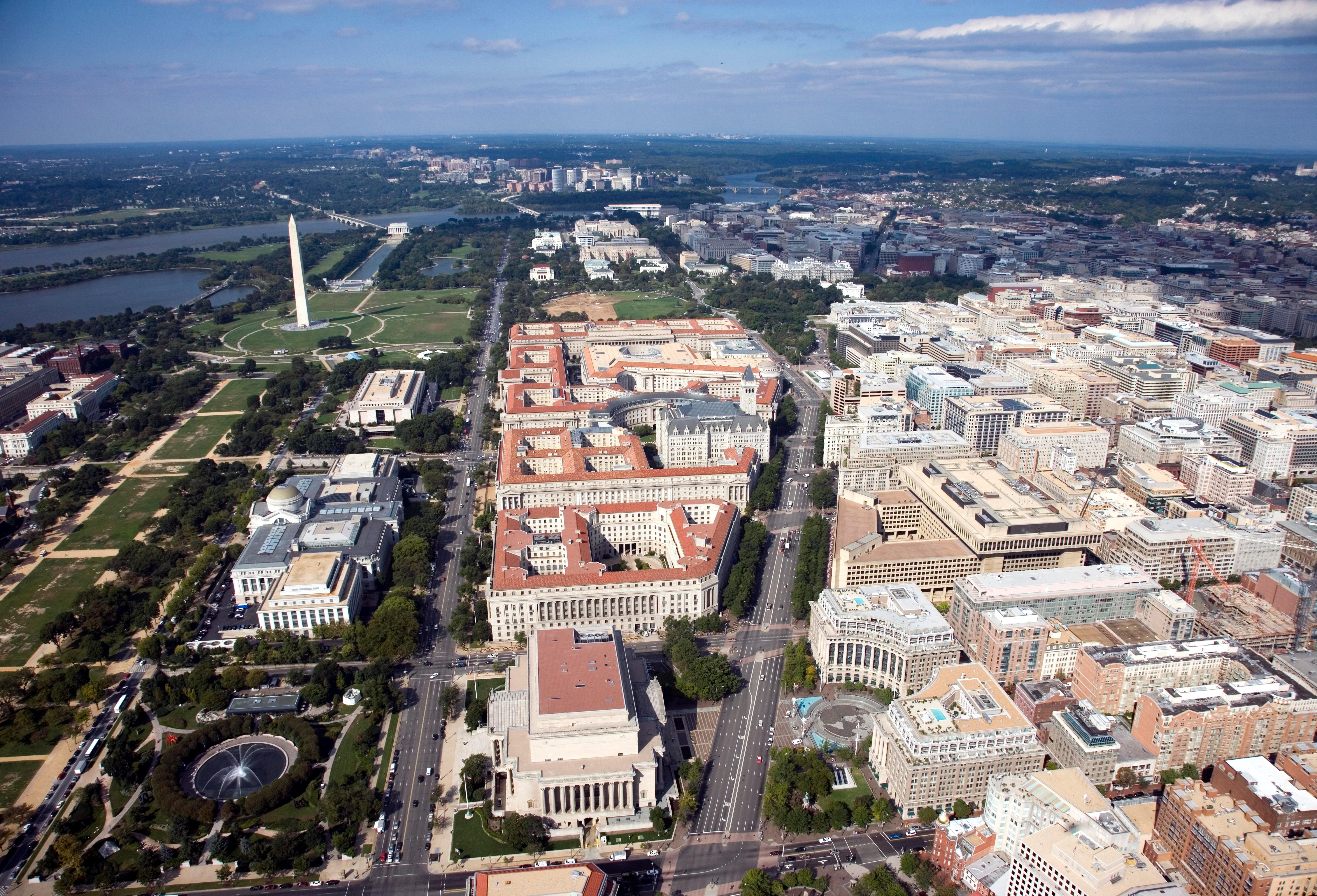 Aerial view of Pennsylvania Avenue (center right) and the Federal Triangle (center) – facing west towards Arlington County, Virginia – in Washington, D.C. Visible landmarks include the National Archives Building (center bottom), Constitution Avenue (center left), the National Museum of Natural History (left), and the Washington Monument (upper left), among other sites, located on the National Mall (left). Photo taken on September 20, 2006.