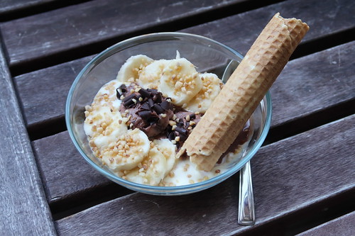 Choco-Chip-Eis mit Vanillesoße, Banane, Haselnusskrokant und Waffelröllchen
