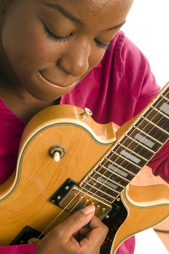 young woman playing guitar with emotional depth