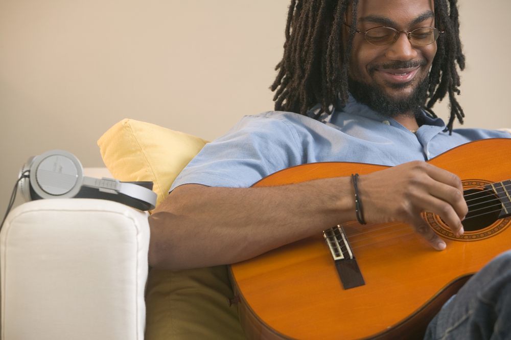 photo of man smiling while practicing guitar