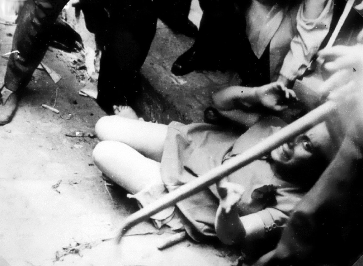 Еврейка сидит у ног бойцов «Украинской народной милиции» ОУН(б) во время погромов во Львове. 30 июня-2 июля 1941