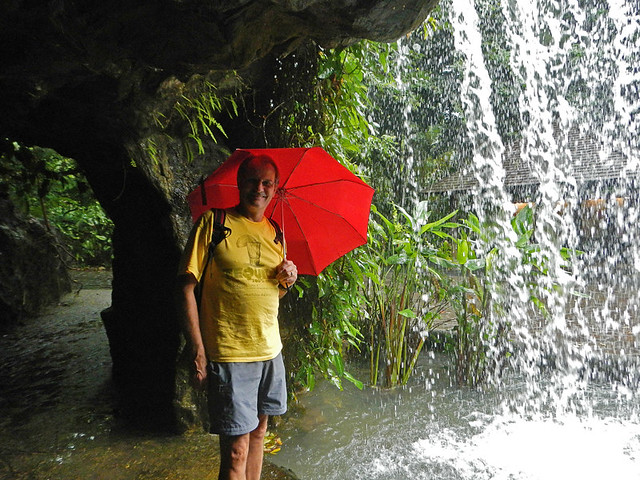 Standing under a waterfall with a red umbrella in Singapore Botanical Garden