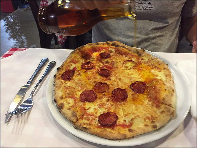 Adding olive oil to pizza at La Casina Rossa Restaurant