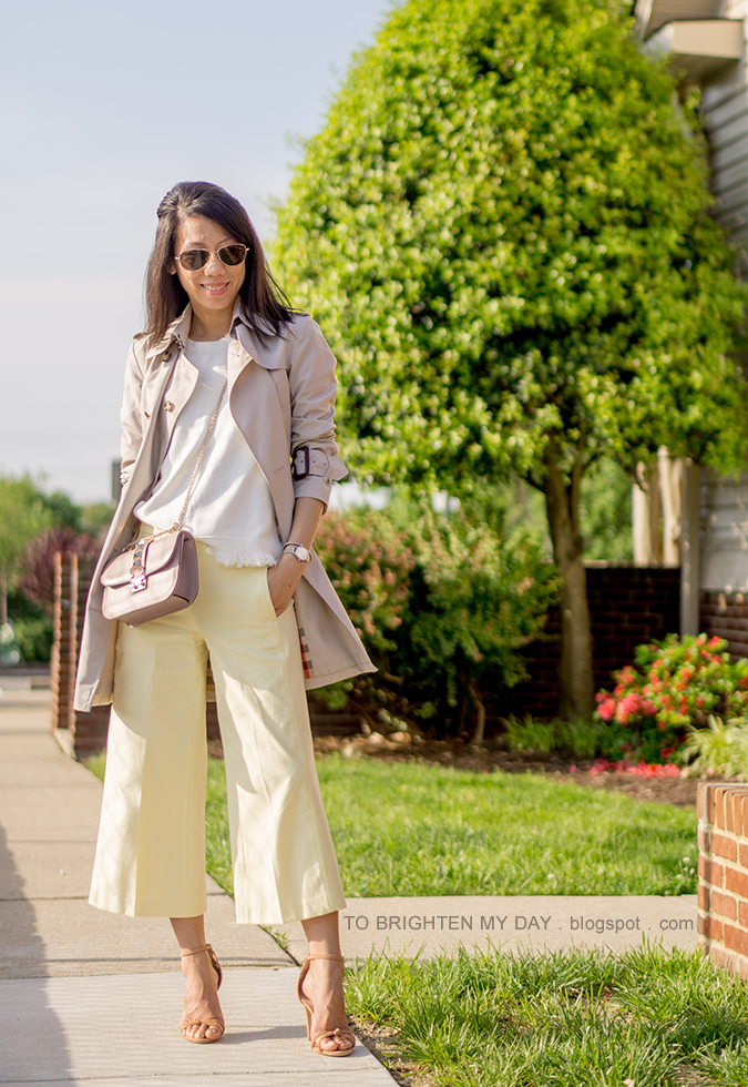trench coat, white sweater tee, nude crossbody bag, two tone watch, silver cuff, yellow wide leg cropped pants, brown knot sandals